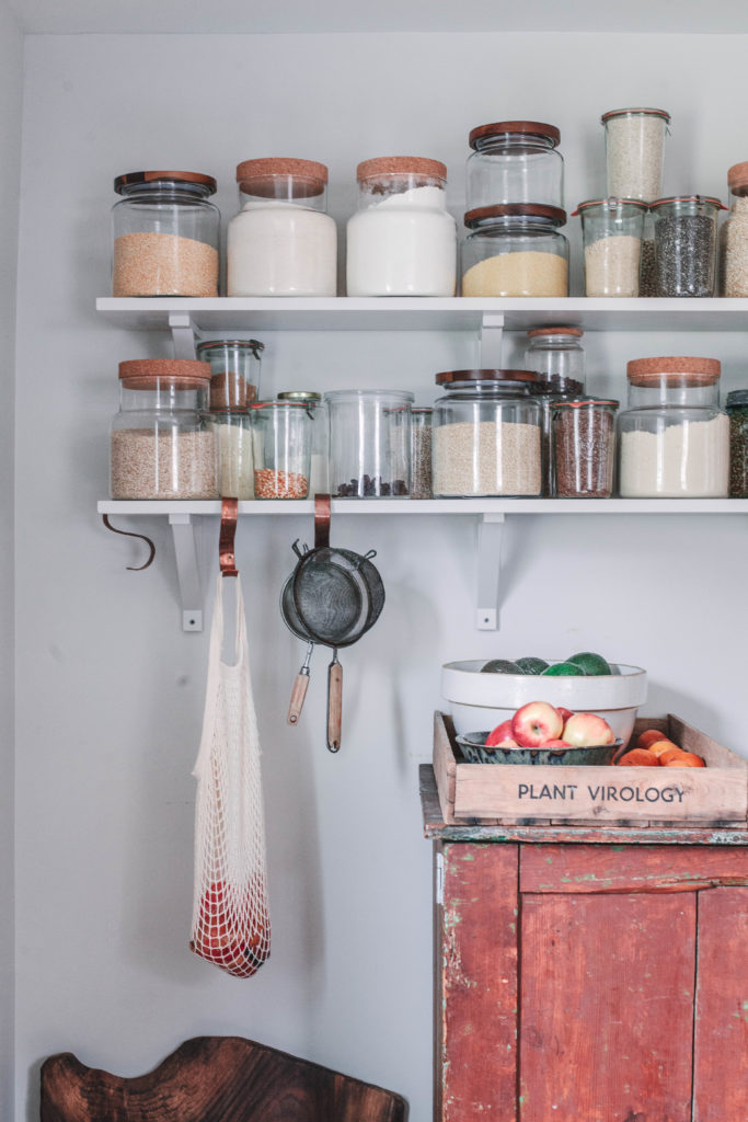 An open pantry shelf with jars of dry goods.