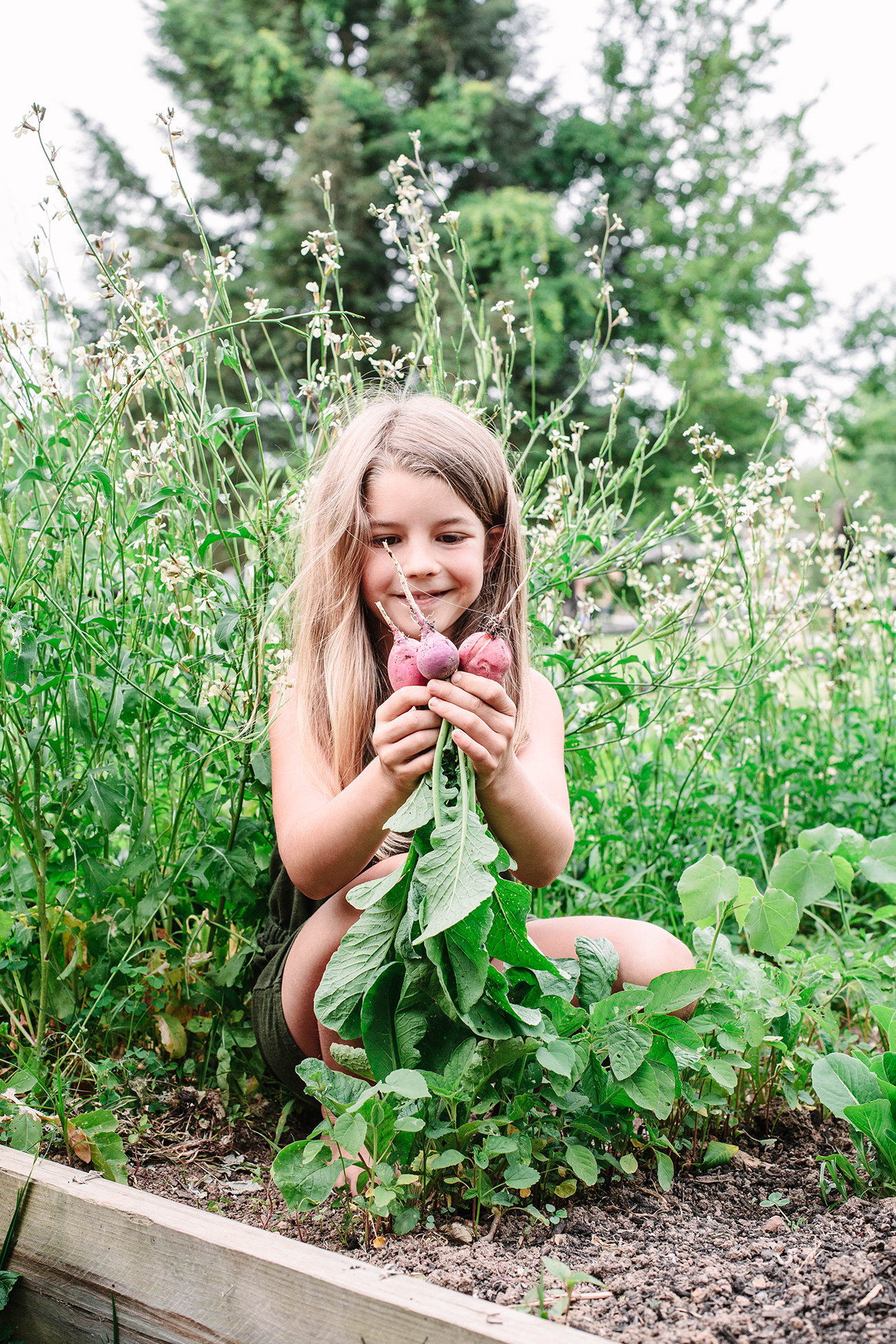 child smiling with joy after picking radishes from garden