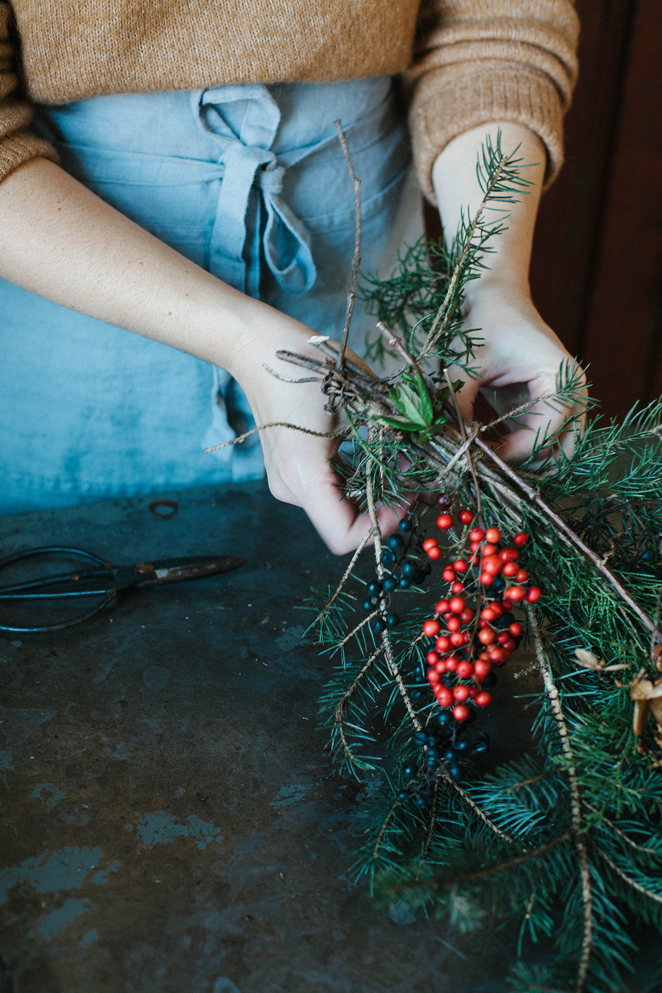 Tying together branches and berries to finish a wreath