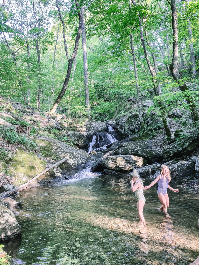 Girls splashing in shallow water at the base of a small waterfall