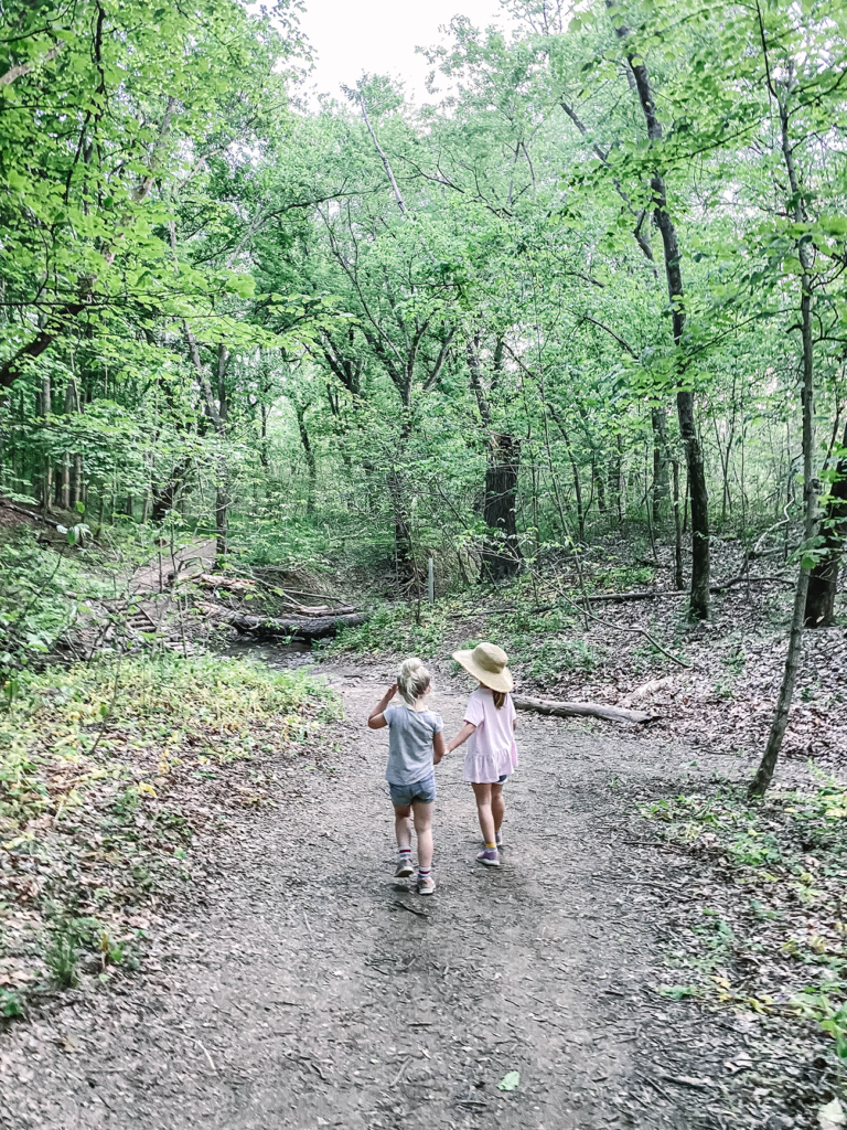 Girls holding hands walking on a path in the woods